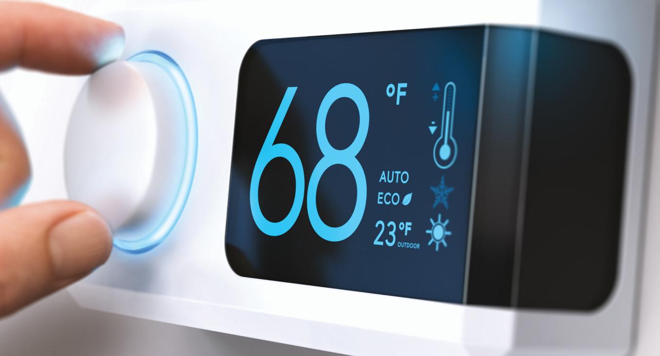 Fingers adjusting the dial on a smart digital thermostat