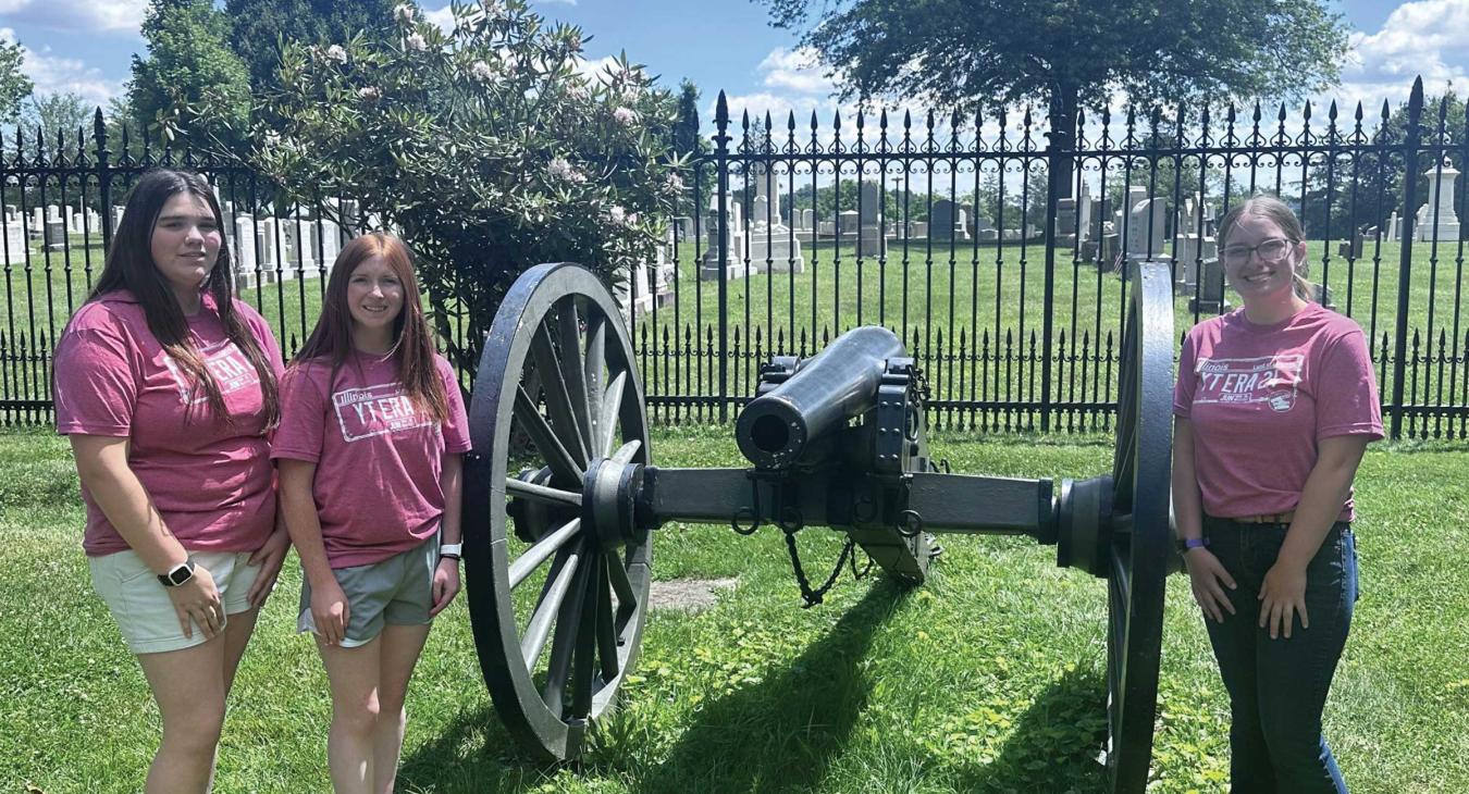 Three girls in pink shirts posing with a Gettysburg cannon