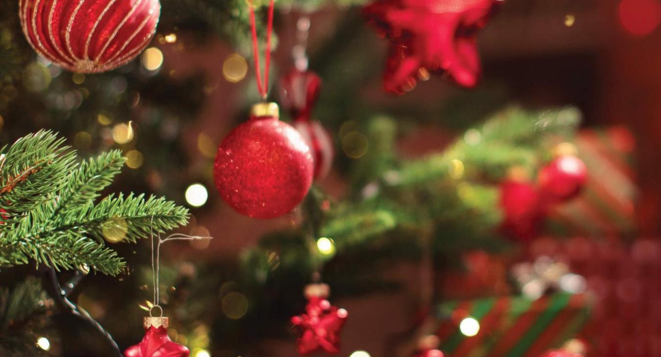 Red ornaments hanging from a christmas tree.