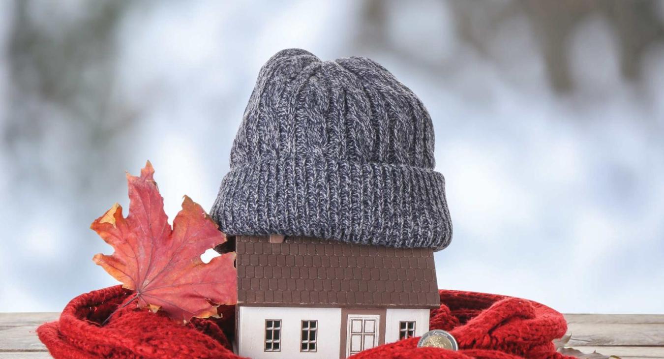 Small wooden house wrapped in a scarf and winter cap