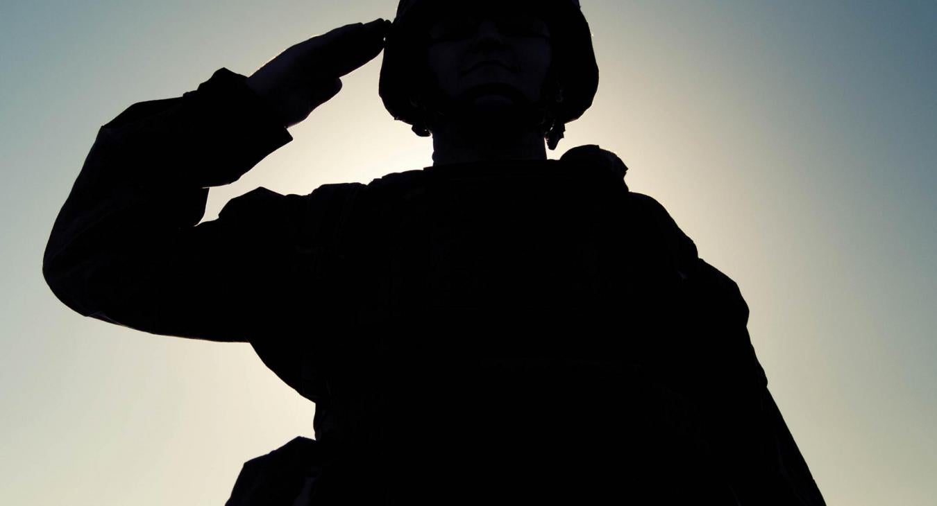 Silhouette of a man in military uniform saluting