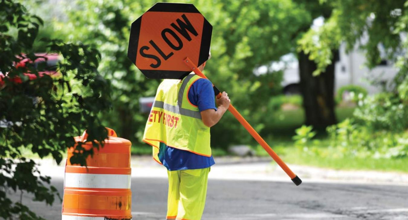 Worker wearing yellow safety vest and holding a slow traffic sign